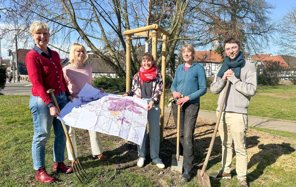 Ingenieurinnen mit Plan und Gartengerät vor neuem Baum im Park