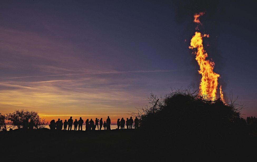 Fotografie eines Osterfeuers mit Menschen im Hintergrund